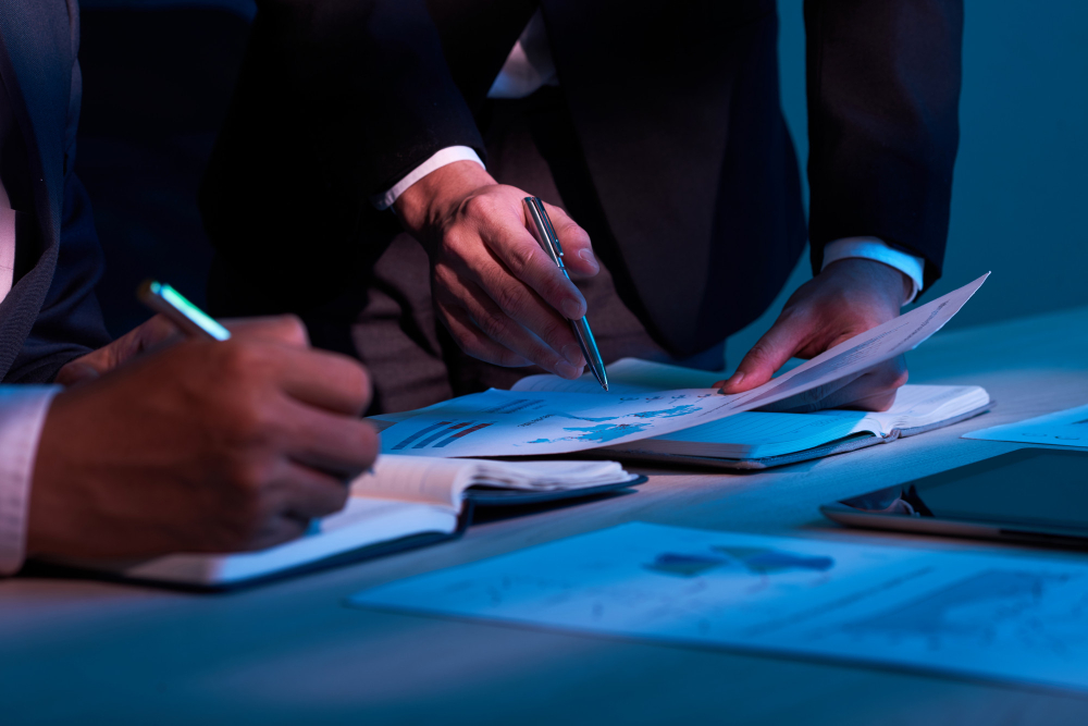 Profissionais analisando documentos e gráficos durante reunião de planejamento estratégico em ambiente corporativo.