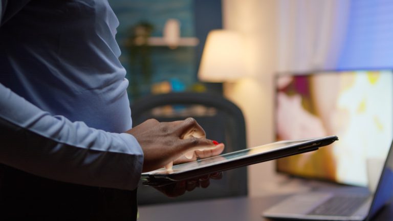 Profissional utilizando um tablet ao lado de um notebook em ambiente de trabalho, representando a gestão de serviços digitais.