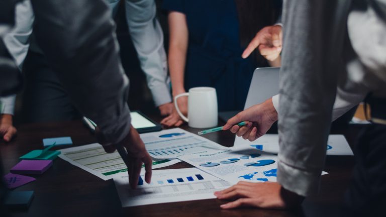 Profissionais analisando gráficos e relatórios durante uma reunião, representando a escolha do CNAE adequado para empresas do Simples Nacional.